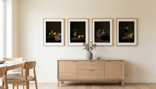Dark Still Life set of 4 — pears, copper and lemons, plums, and wine with bread hung in a row above an oak sideboard in a dining room